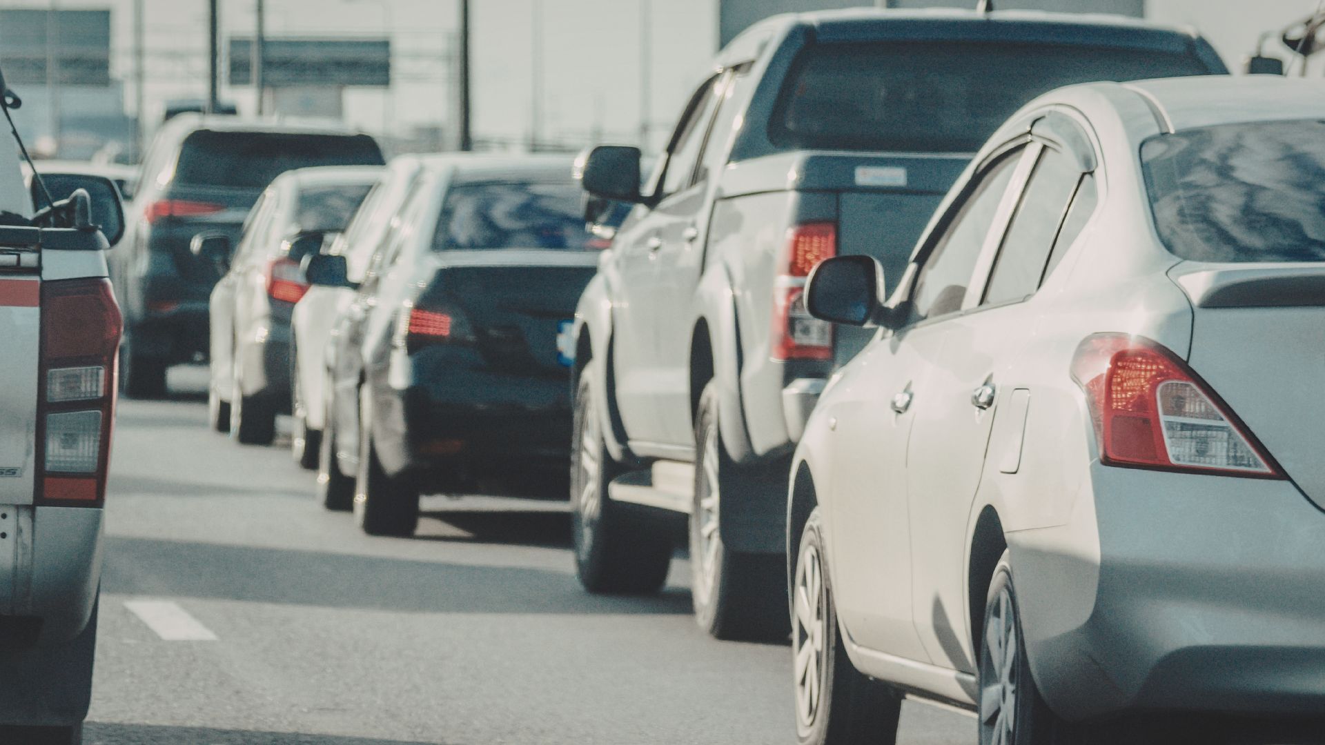 ALT描述: 公路上緩慢移動的車陣近景，銀色轎車與灰色皮卡車緊鄰併行。