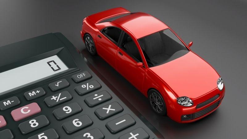 ALT描述: 一輛精緻的紅色玩具轎車模型停在一個黑色的辦公計算機旁，兩者都放置在平滑的灰色桌面上，計算機螢幕顯示為「0」。