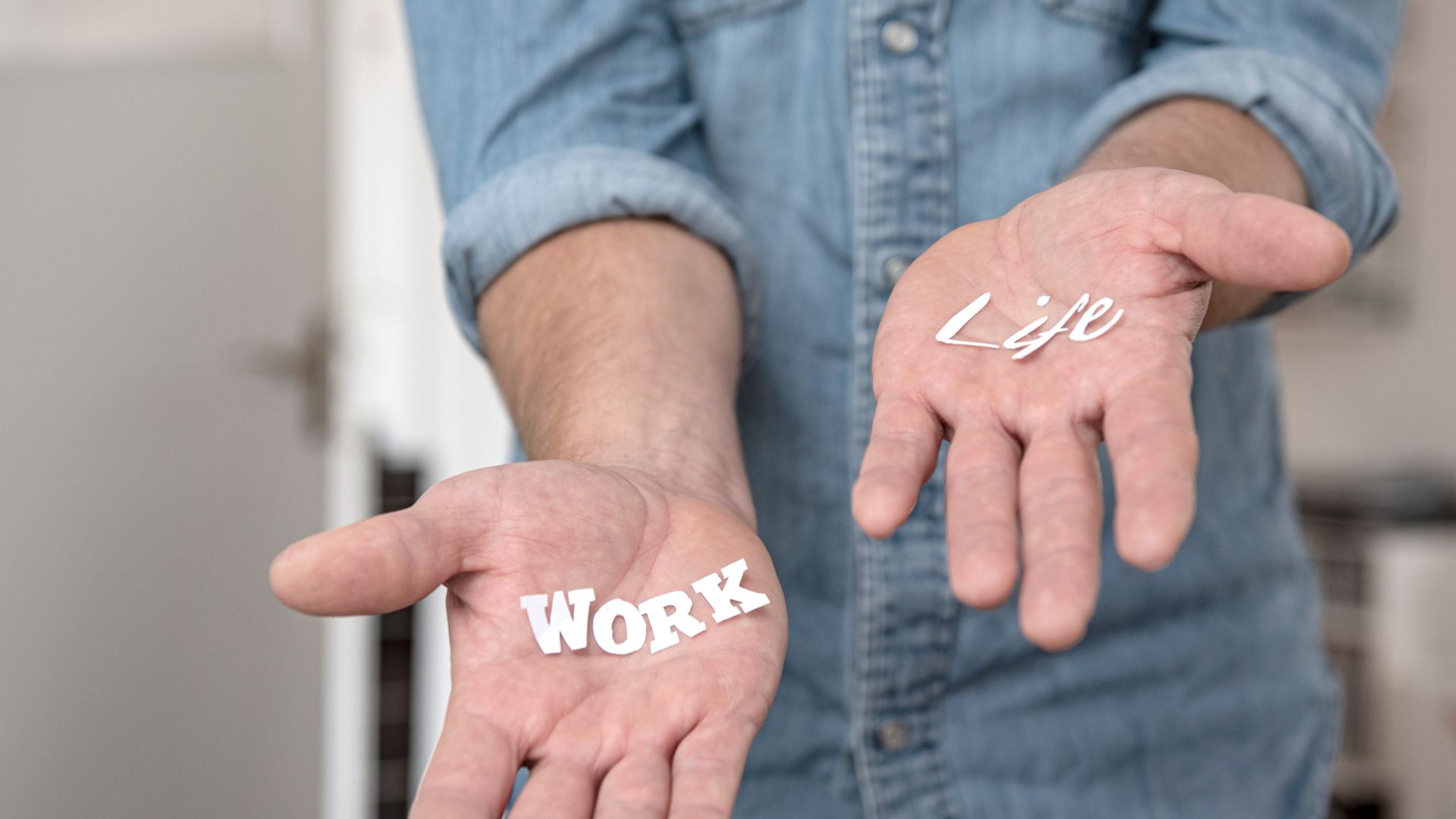 ALT描述: 一個人的雙手掌心向上平舉，左手心放著白色字樣「WORK」，右手心放著「LIFE」，象徵工作與生活的平衡。