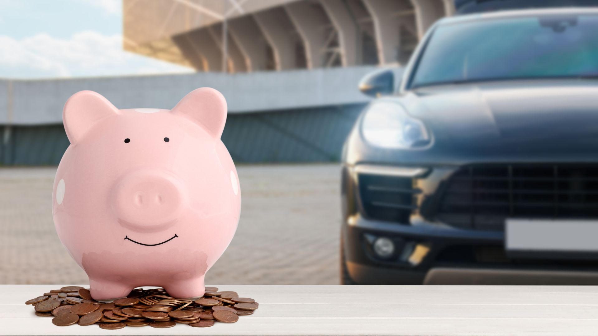 ALT描述: 粉紅色小豬撲滿放在堆疊的硬幣上，背景是模糊的黑色高級車，代表購車儲蓄計畫。